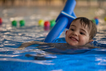 Happy child smiling and learning to swim with floatation device