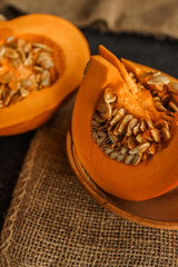 Fresh pumpkin slices with visible seeds on a ceramic plate and burlap cloth, creating a rustic, natural food composition