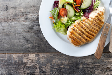 Healthy grilled chicken with salad on wooden table. Top view. Copy space