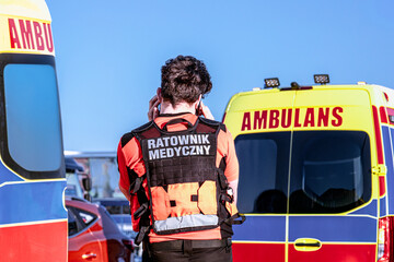 Polish paramedic in a vest reading "Emergency Medical Service" ("Ratownik Medyczny") at the site of a car crash.
