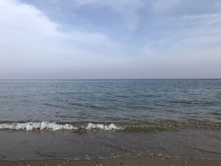 A calm view of the sea to the horizon, a coastal strip, whitecaps on the sea, background, texture