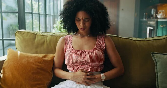 Pain, sick and woman with stomachache, home and menstrual cramps in living room, massage or health. Lounge, uncomfortable and person with pelvic inflammatory disease, abdominal and infection in house
