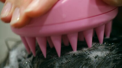 Slow motion close up woman massaging wet hair pink silicone scalp brush, applying shampoo and creating gentle cleansing motion during personal beauty routine. Concept massage and care on hair. 