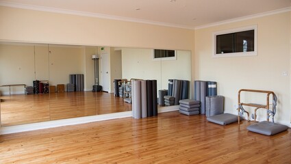 Obraz premium Inviting yoga studio with wooden floors mirrors and neatly stacked mats and cushions for relaxation and mindfulness