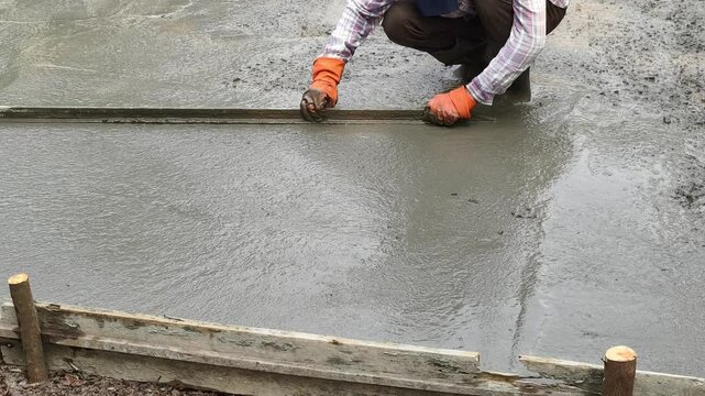 Cast-in-place work using trowels. Workers level cement mortar. Construction worker uses trowel to level cement mortar screed. Concrete works on construction site

