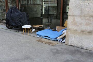 Campement de sans-abri devant une vitrine de magasin
