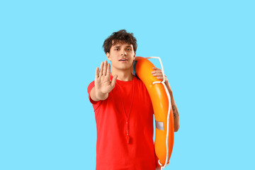 Male lifeguard with ring buoy showing stop gesture on blue background
