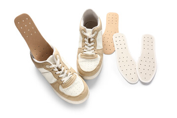 Pair of stylish sneakers and orthopedic insoles isolated on white background