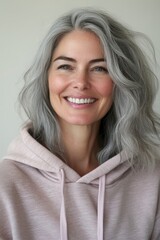 Fototapeta premium Confident Mature Woman with Silver Gray Hair Wearing a Pink Hoodie