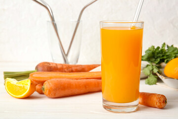 Glass of fresh carrot juice with parsley and orange on white wooden table