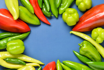 Frame made of different fresh peppers on blue background