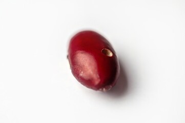 Close-up of a red kidney bean shows a small hole, possibly caused by pests or damage.