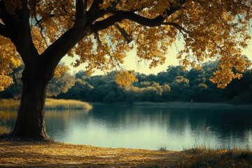 A huge tree with golden leaves towers over a calm and reflective lake. Use this landscape for nature, peace, relaxation, and autumn themes.