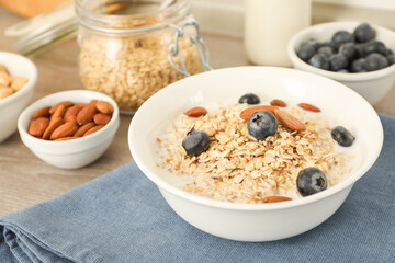 Tasty oatmeal with milk, blueberries and almonds in bowl on table, closeup