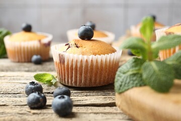 Delicious muffins with blueberries and mint on wooden table, closeup