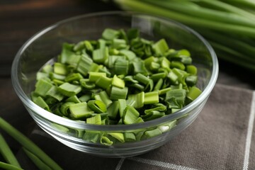 Cut fresh green onions in bowl on table, closeup