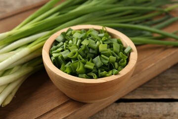 Fresh green onions on wooden table, closeup