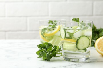 Healthy drink with parsley, cucumbers, lemon and celery on white marble table, closeup. Space for text