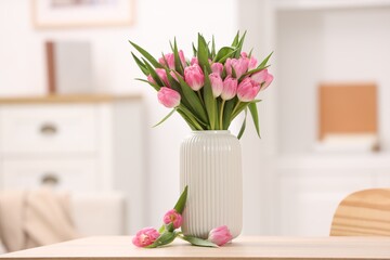 Bouquet of beautiful tulips in vase on wooden table indoors