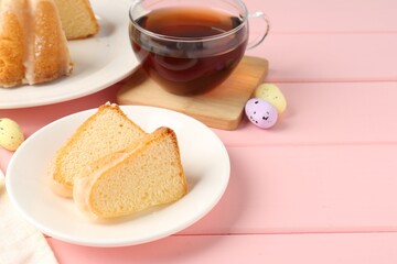 Pieces of delicious bundt cake, Easter eggs and tea on pink wooden table, closeup