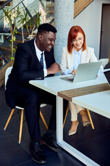 Two Business Professionals Collaborating on a Laptop in a Modern Office Setting