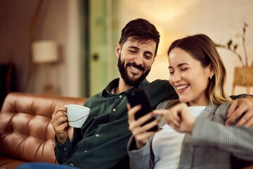 Happy Couple Relaxing and Laughing While Using a Mobile Phone