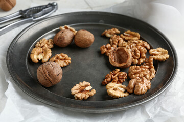 Plate of tasty walnuts on table