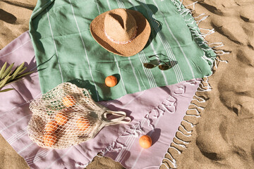 Straw hat, sunglasses, towel, bag on beach sand background. Aesthetic lifestyle, summer vacation concept. Sunbathing, beach party set, holiday picnic. Travel fashionable blog, social media, top view.