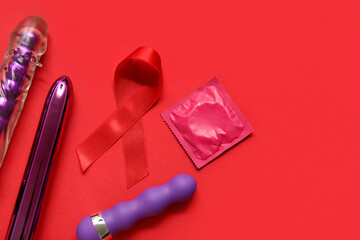 Red ribbon with sex toys and condom on color background. AIDS Day concept