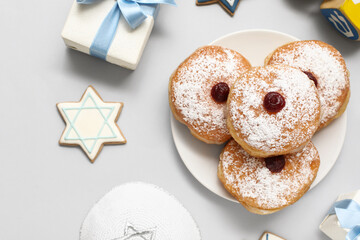 Plate with tasty donuts and gifts for Hanukkah celebration on grey background
