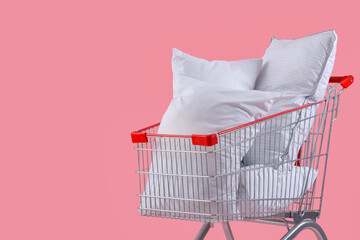 Shopping cart full of pillows on pink background
