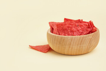 Bowl with red nachos on yellow background