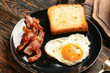 Plate with tasty bacon, heart made of fried egg and toast on wooden background, closeup