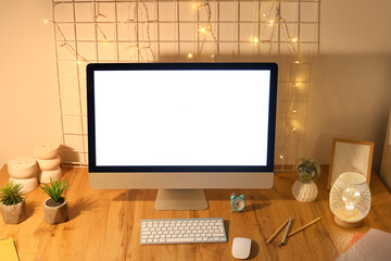 Fototapeta premium Workplace with blank computer monitor, pin board and glowing lights in office at night