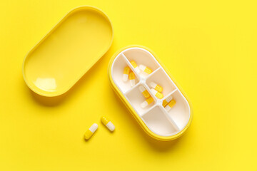 Container with pills on yellow background