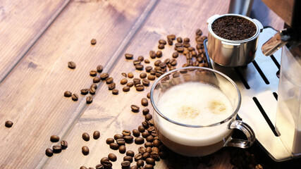 Cappuccino in glass cup and coffee machine on pink wooden background
