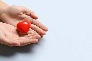 Female hands with red heart on grey background