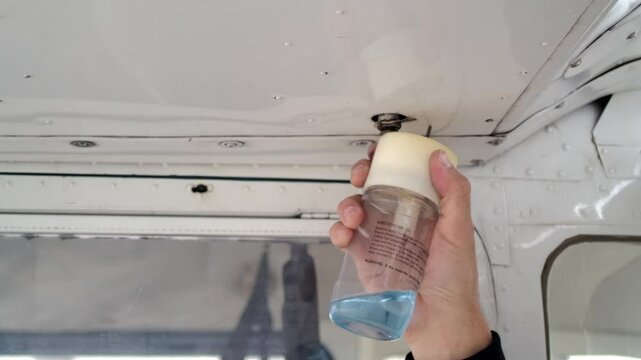 Close Up Pilot Hand Using Fuel Drain Cup - Airplane Preflight Check