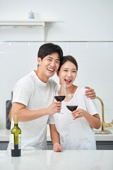 Fototapeta premium A young newlywed couple enjoying wine at the kitchen table on holiday, having a happy time.