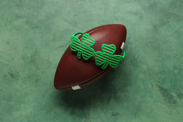 Rugby ball with clover shaped party glasses on green grunge background. St. Patrick's Day...