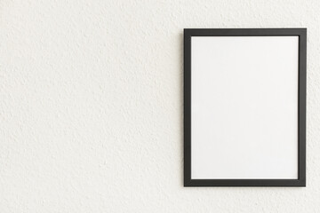 Blank black photo frame on light wall