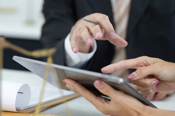 Legal Consultation and Digital Engagement. A lawyer guiding a client through documentation on a tablet during a meeting.