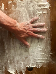 Fototapeta premium man hand laying on wooden cutting board with flour, top view, copy space