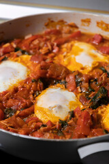 close-up of freshly cooked shakshuka, a flavorful dish with poached eggs in a rich tomato sauce, served in a pan. perfect for a hearty and delicious breakfast.