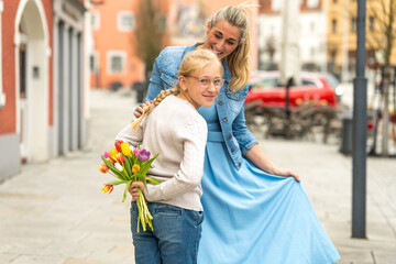 Fototapeta premium A girl presents flowers to her happy mother on Mother's Day