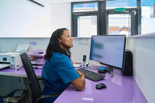 Dental clinic receptionist managing appointments and patient information on computer