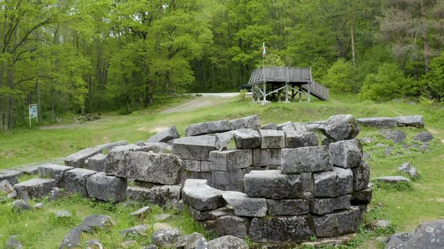 Panning from the left to the right showing some blocks of rocks scattered around the ruins of the ancient tomb of Mishkova Niva at the foot of Strandzha mountain in Bulgaria.
