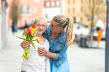 Fototapeta premium Smiling daughter gifts her mother a bouquet of flowers for Mother's Day