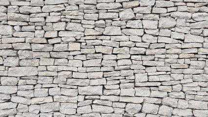 A wall made of natural white stone. A modern stone fence.