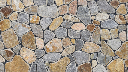 A large wall made of natural granite stones of different sizes and colors of gray texture. A unique...